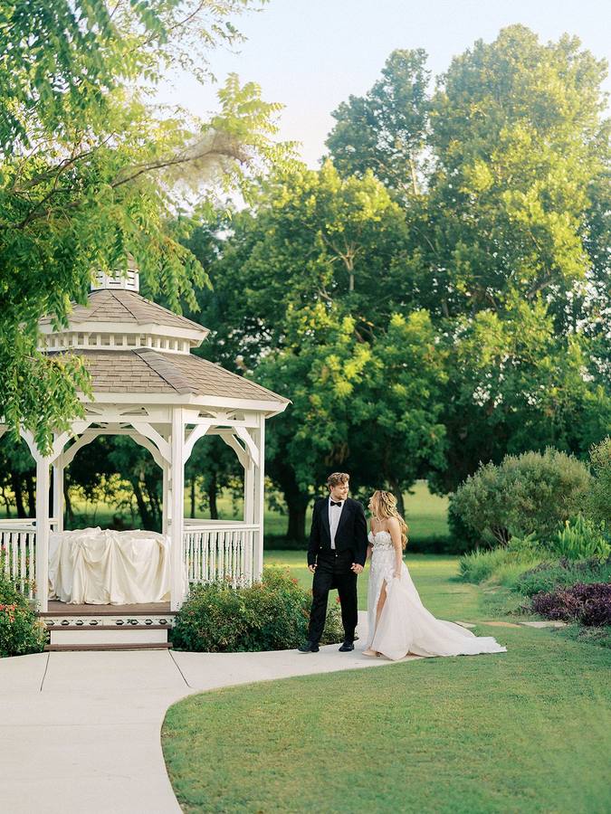 Couple walking the garden path beside the gazebo at River Road Venue