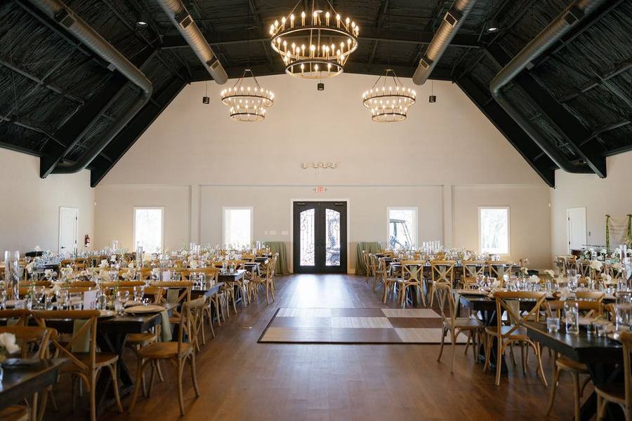 Reception hall set with farm tables, chandeliers, and cross-back chairs