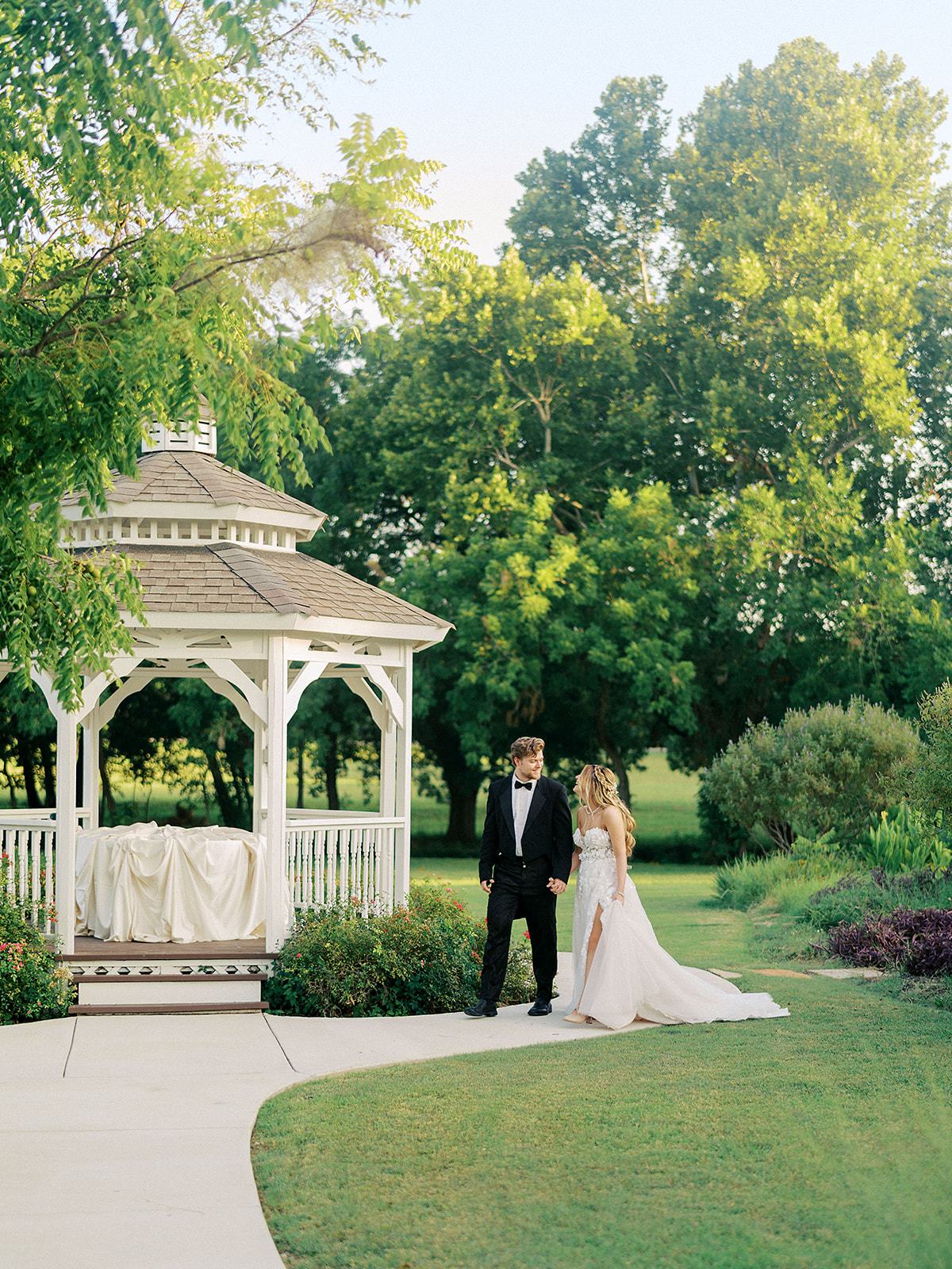 Couple walking the garden path beside the gazebo at River Road Venue