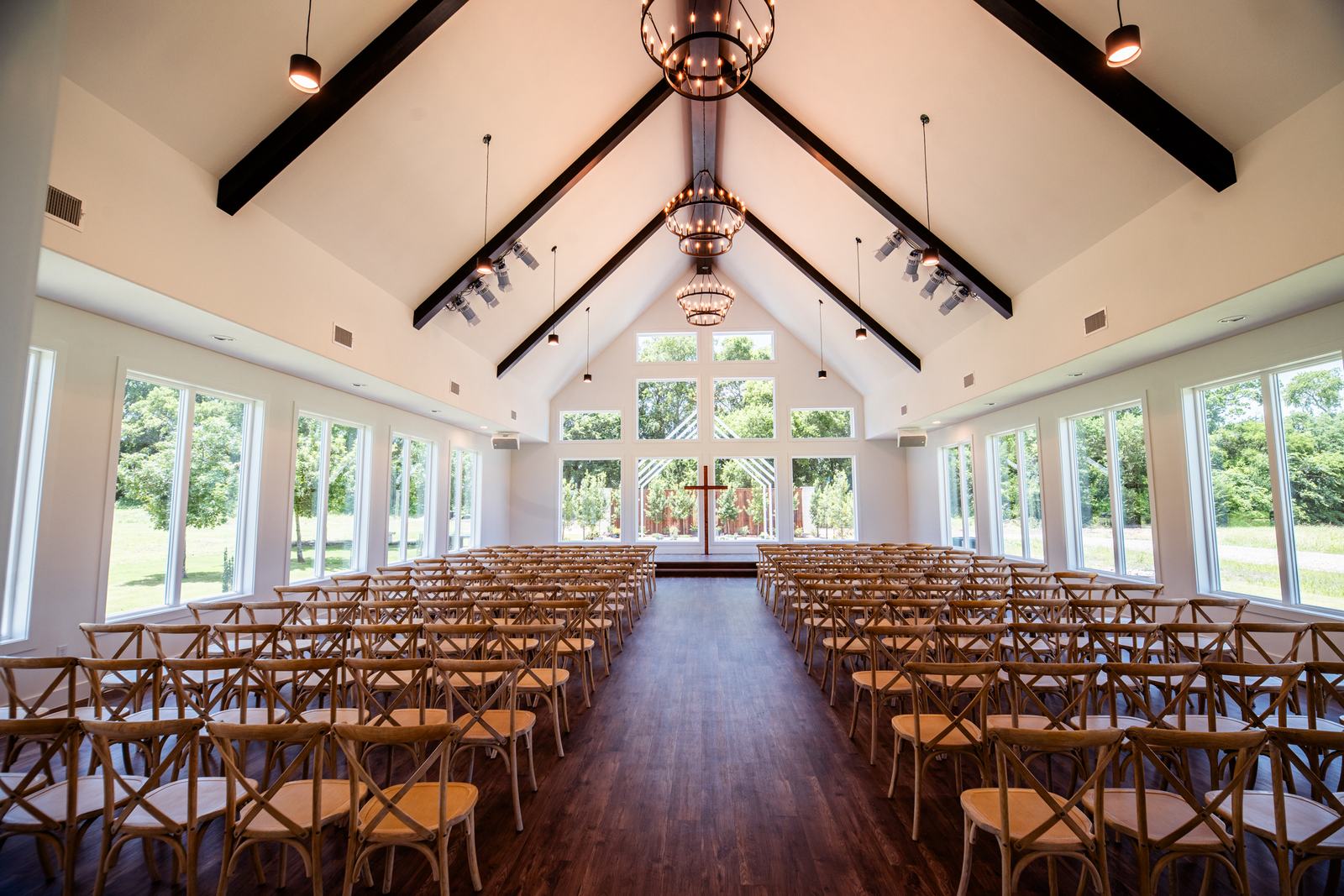 Chapel interior with wooden chairs, tall windows, and a wooden cross